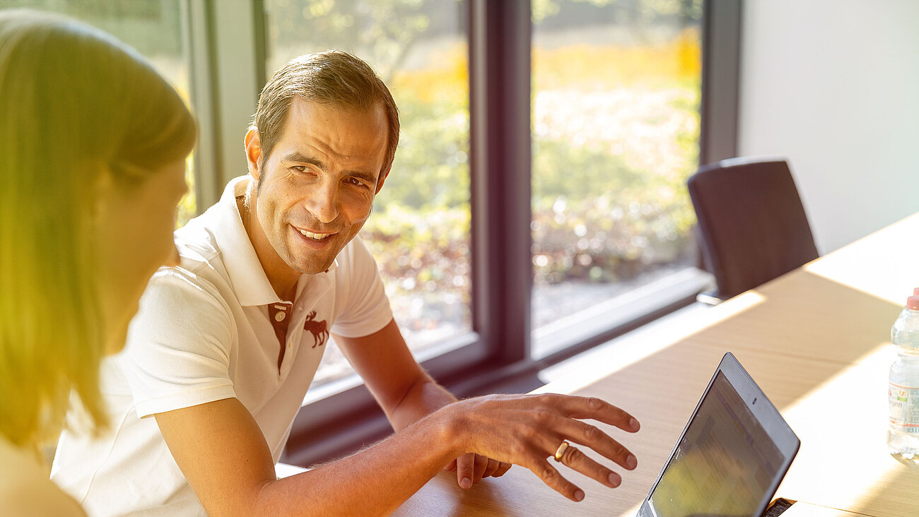 Ein Mann sitzt an einem Tisch mit einem Laptop.