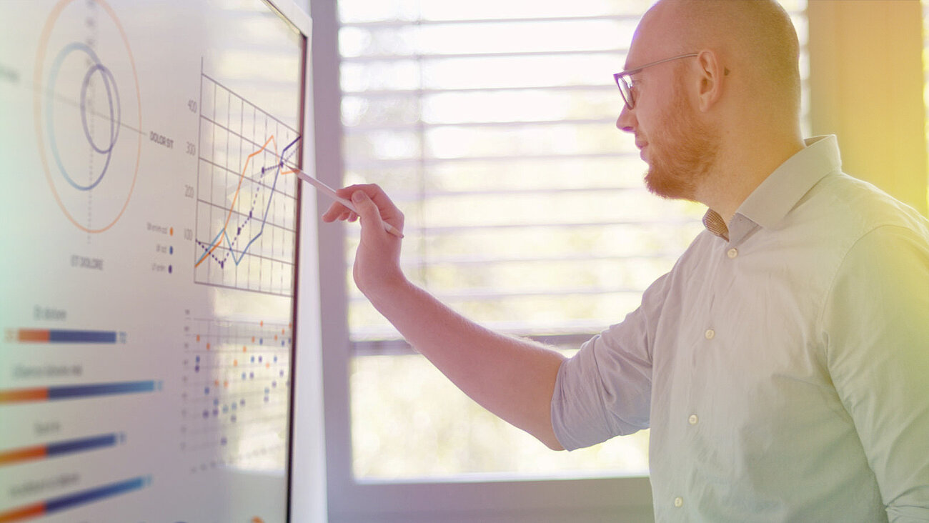 A man pointing to a board with graphs and diagrams.