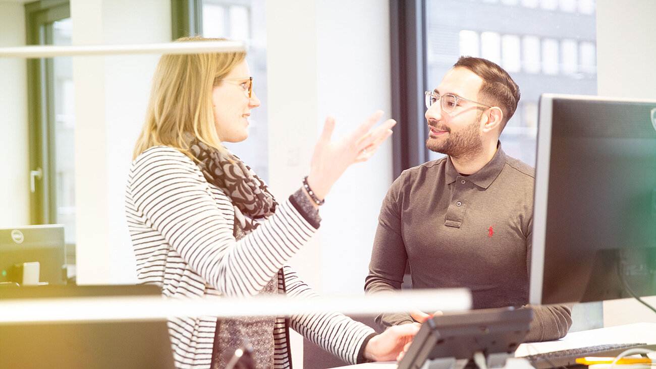 Ein Mann und eine Frau unterhalten sich in einem Büro.