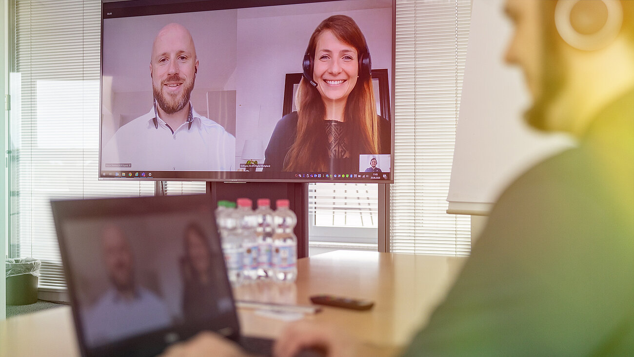 Ein Mann und eine Frau haben ein Videotelefonat. Sie lächeln und unterhalten sich über den Bildschirm.